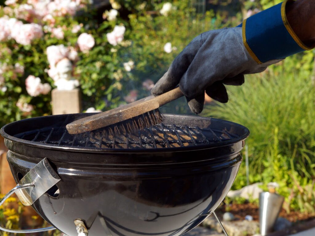 Person cleaning grill with brush