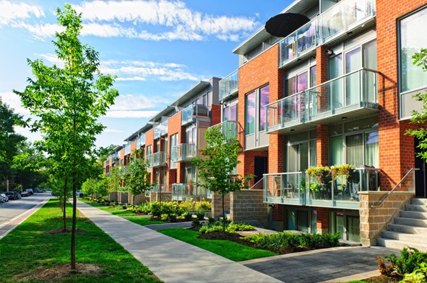 Sidewalk view of several townhomes down a residential street