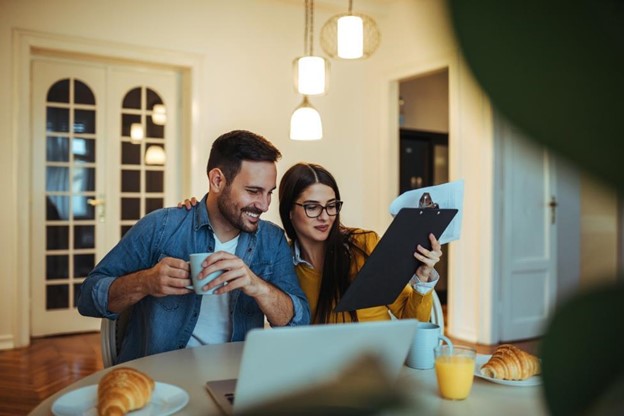 Couple sitting down for breakfast with a laptop and clipboard
