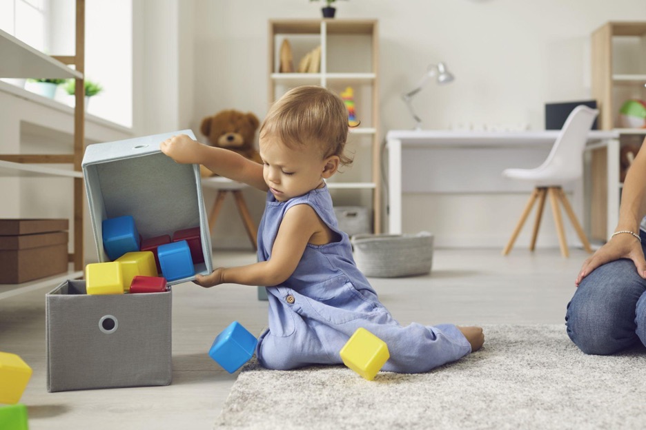 child dumping blocks from one fabric bin into another