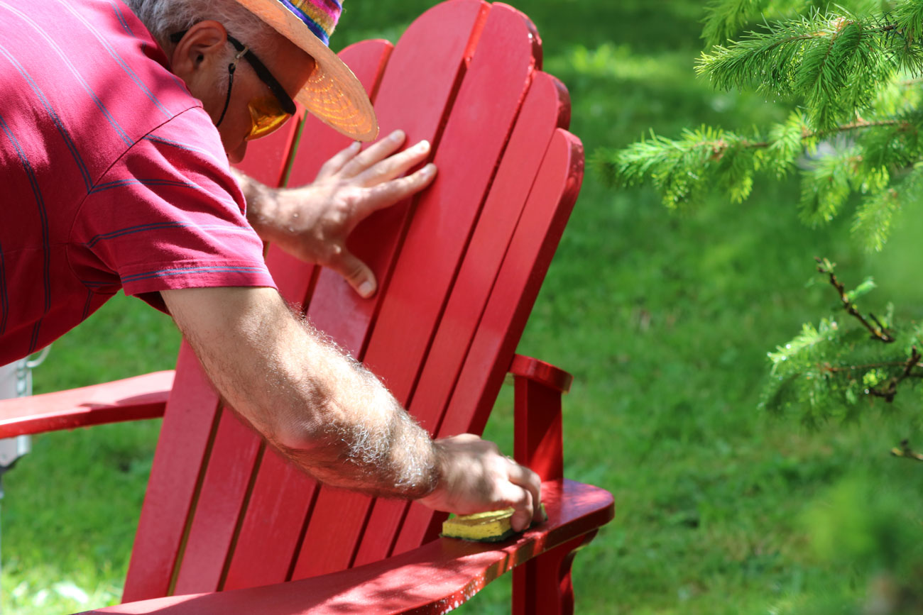 Man cleaning an Adirondack chair.