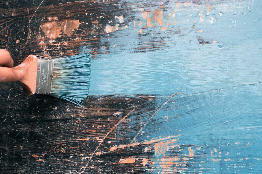 Person using a paint brush with blue paint