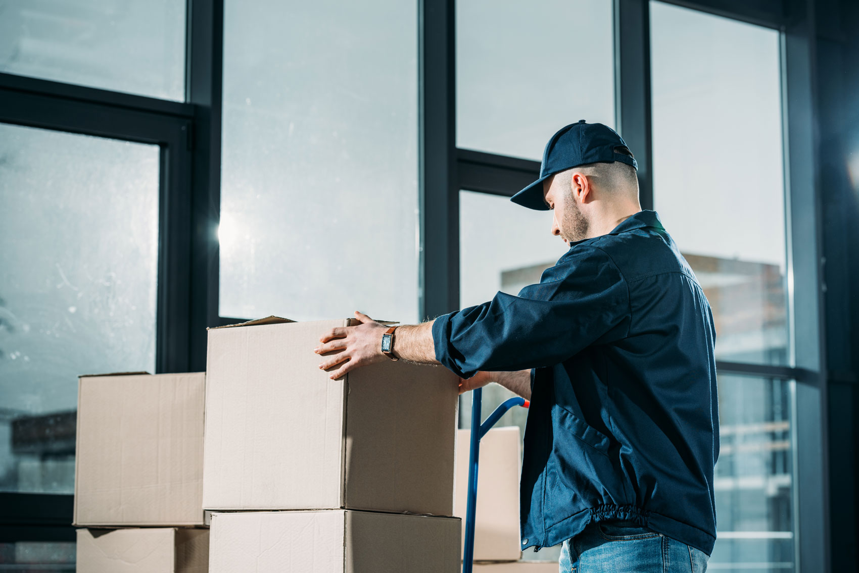 Man stacking cardboard boxes on handcart