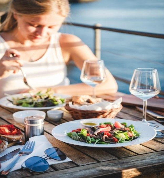 A woman eating on a table by the water
