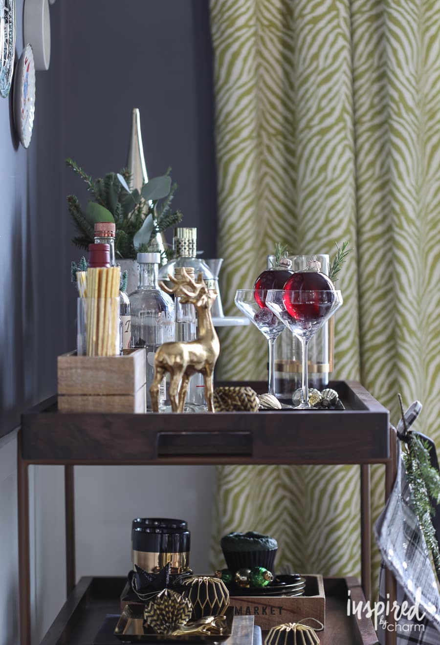 Bar cart featuring clear ornaments filled with a red cocktail set inside coupe glasses.
