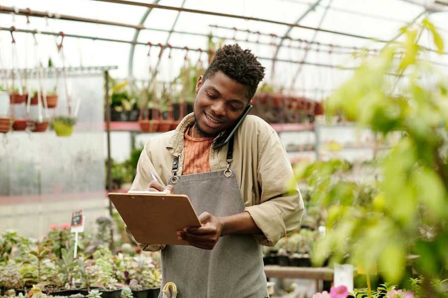 Manager using an iPad in a greenhouse to track inventory