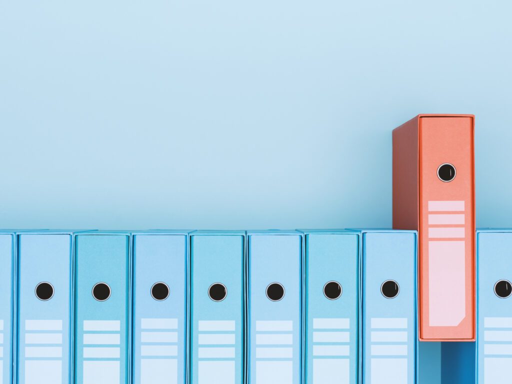 Organized archive with ring binders in a row, one is red: archive, database and search concept